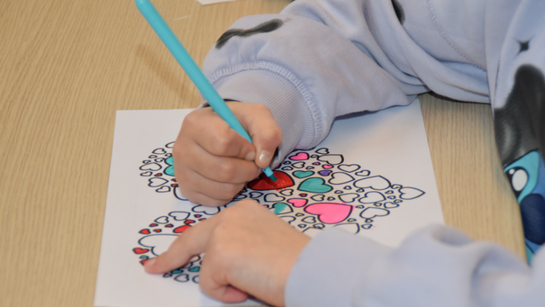 Les enfants colorient un grand coeur fait de petits coeurs pendant le culte de l'enfance